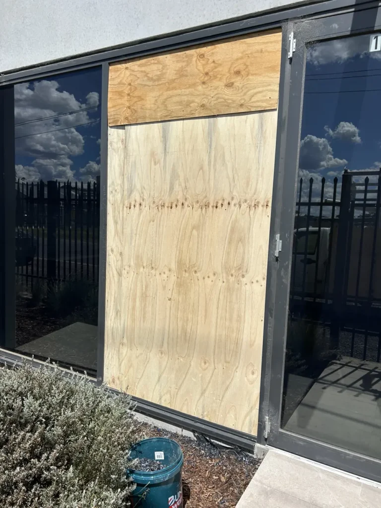 Commercial window secured with temporary plywood boarding by ACW Glazing & Maintenance