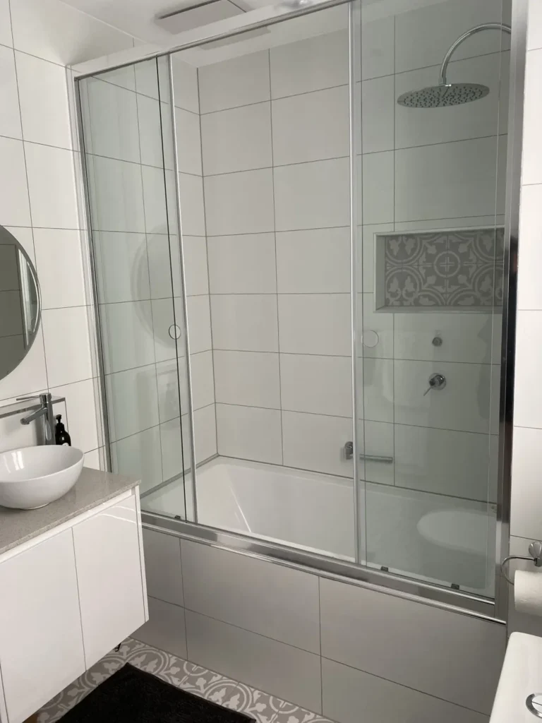 Side view of a framed glass screen above a bathtub