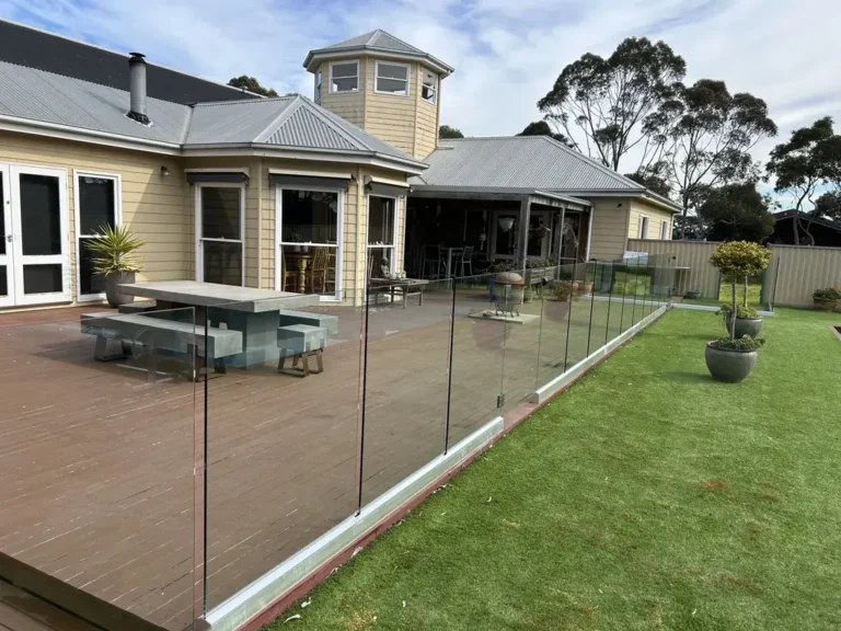 Wide view of glass pool fencing between a paved outdoor area and lawn