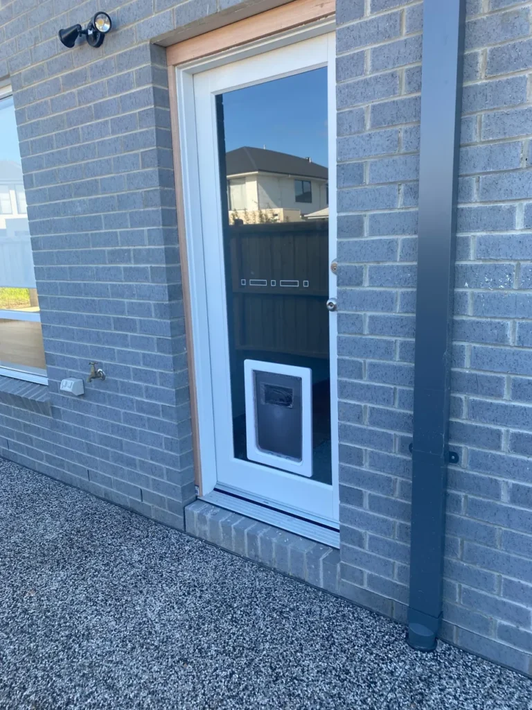 White pet door fitted near the bottom of a white framed glass door
