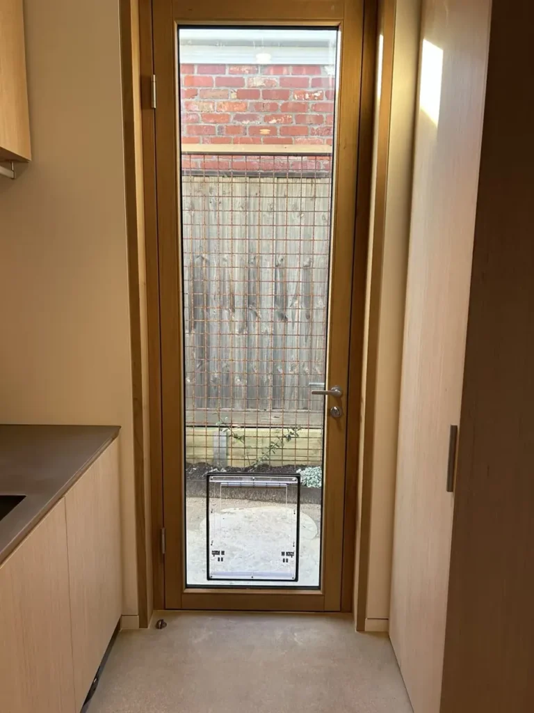 Full view of a tall glazed panel with a pet door fitted near the bottom