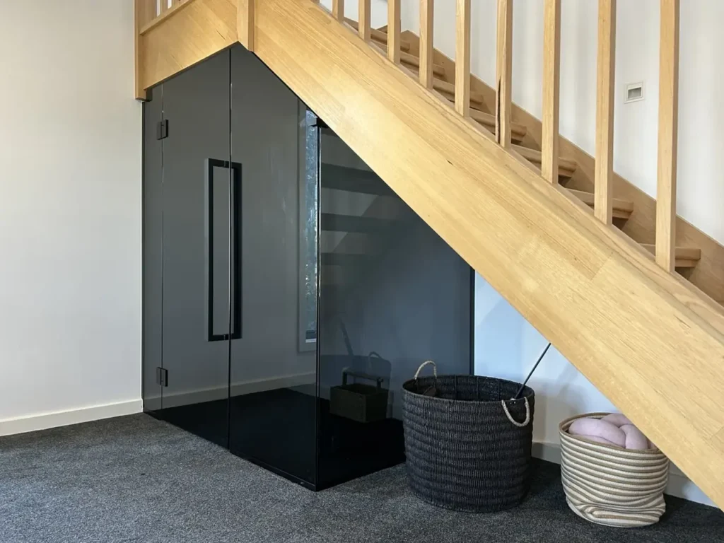 Custom grey glass enclosure beneath a timber staircase